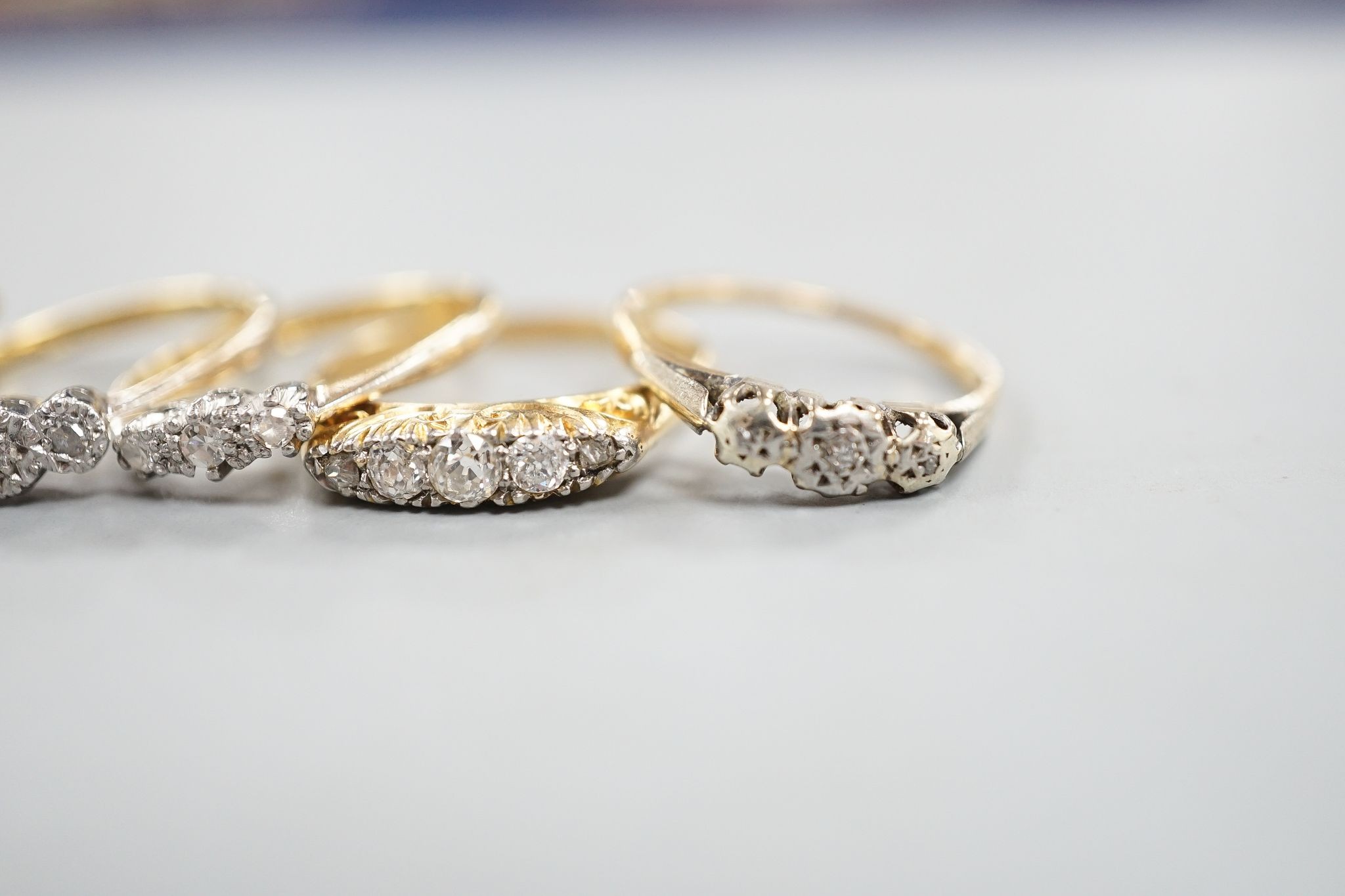 An early 20th century yellow metal and graduated five stone diamond set half hoop ring, size Q, gross 3.8 grams, three other 18ct and diamond chip set rings, gross 8 grams and a 9ct and diamond chip ring, gross 1.2 grams